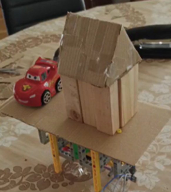 La casita LEGO final sobre la plataforma con servo y Arduino — el capstone del curso. Cierra la trayectoria completa que recorrió la materia: del CSV en Plotly (T1) al sismo que sacude un objeto físico. Cada cápsula técnica añadió una pieza, y aquí están todas juntas funcionando — datos, interactividad, sonificación, fisicalización.